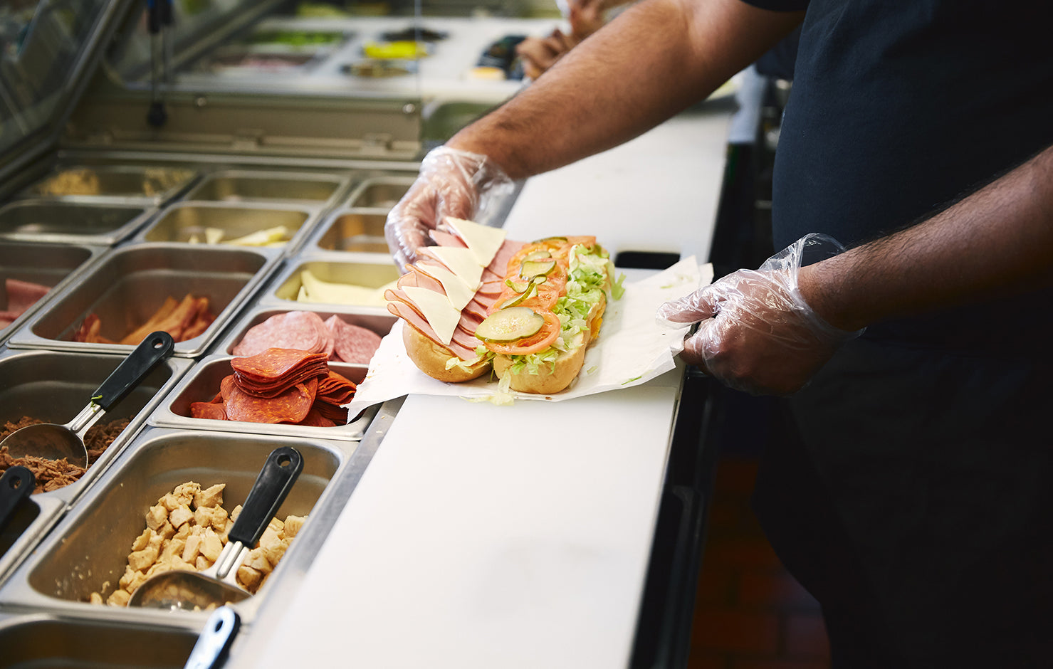 Chef preparing sandwich on a prep table 